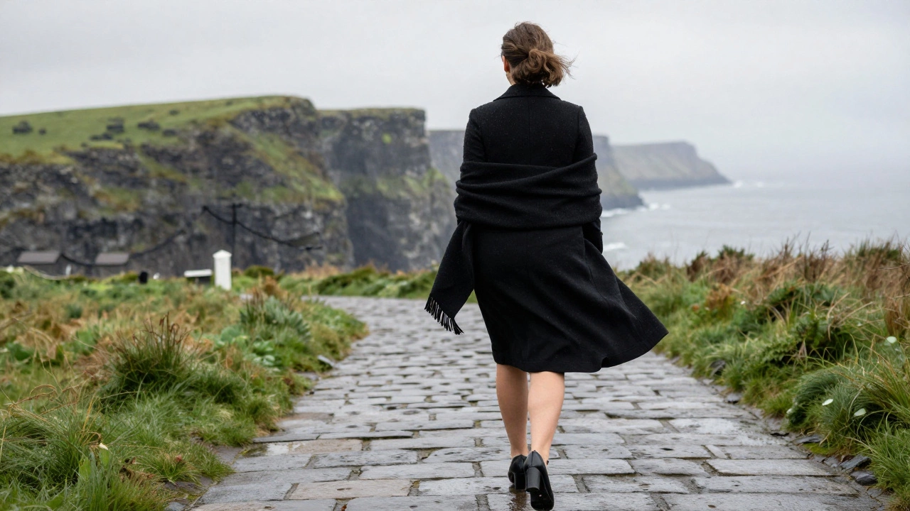 A woman walking on wet cobblestones toward a wedding venue, wearing a sleek black dress with a slight train and block heels, wrapped in a matching wool shawl.
